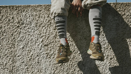 meilleures chaussettes chauffantes grises G HEAT portées avec des chaussures de trail sur un muret